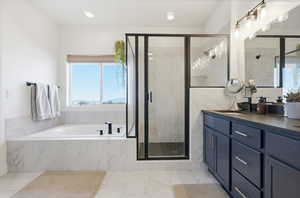 Full bathroom featuring a marble finish shower, a bath, double vanity, and recessed lighting