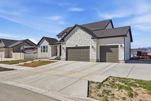 View of front of house with an attached garage, driveway, and stone siding