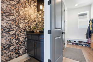 Bathroom with vanity, light wood finished floors, and wallpapered walls