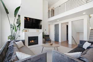 Living area featuring wood finished floors, a high ceiling, a glass covered fireplace, and recessed lighting