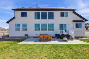 Rear view of house with a patio, roof mounted solar panels, stucco siding, and outdoor dining area