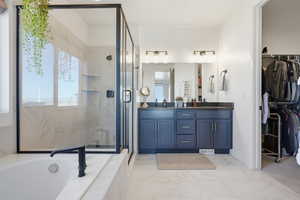 Bathroom with double vanity, a spacious closet, a marble finish shower, and a bath