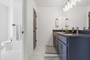 Bathroom featuring double vanity and light marble finish flooring