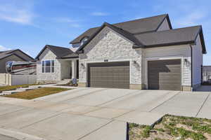 View of front of home featuring an attached garage, driveway, and stone siding
