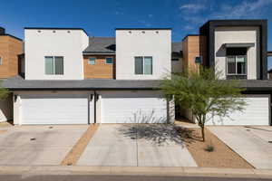Contemporary house with stucco siding, an attached garage, and concrete driveway