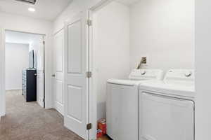 Laundry area featuring light carpet and washing machine and clothes dryer