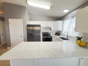 Kitchen featuring tasteful backsplash, Brand New Stove appliance, vaulted ceiling, quartz counter top, and white cabinetry