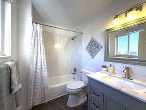 Primary Bathroom featuring vanity, New shower enclosure / tub combo with curtain, and dark tile patterned floor