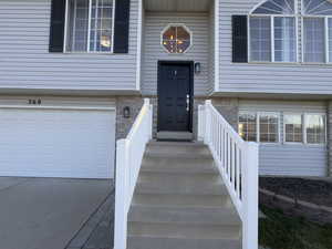 Entrance to property with an attached garage, vinyl, brick siding, and concrete driveway