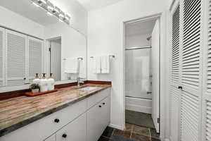Full bathroom with a closet, vanity, and enclosed tub / shower combo