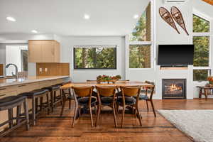 Dining room with dark wood-style flooring, a glass covered fireplace, and recessed lighting