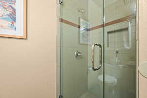 Bathroom featuring a shower stall and a textured wall