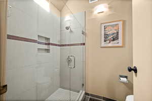 Full bathroom featuring toilet and a shower stall