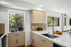 Kitchen featuring cream cabinetry, light stone countertops, black electric range oven, dark wood-style flooring, and decorative backsplash
