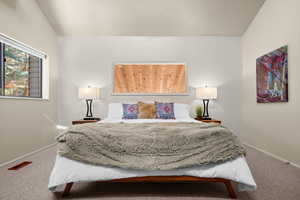Carpeted bedroom featuring vaulted ceiling and baseboards