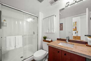 Full bath with vanity, a shower stall, and a textured ceiling