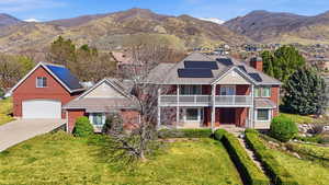 Traditional home featuring a mountain view, driveway, a chimney, solar panels, and brick siding
