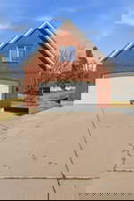 View of side of property featuring brick siding, driveway, and a garage