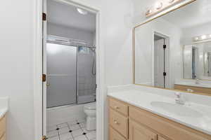 Full bathroom featuring vanity, shower / bath combination with glass door, and light tile patterned flooring