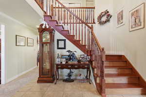 Staircase with ornamental molding and tile patterned flooring