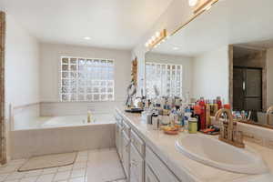 Full bath with a shower stall, double vanity, a bath, and light tile patterned floors