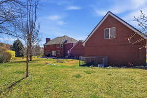 Rear view of property with brick siding, a chimney, a yard, and a patio area