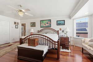 Bedroom with dark wood-type flooring, crown molding, a ceiling fan, and connected bathroom