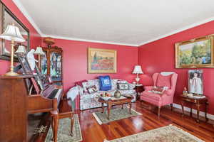 Living area with hardwood / wood-style floors and ornamental molding