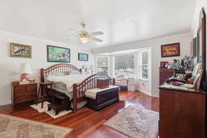 Bedroom featuring dark wood-type flooring, ornamental molding, and ceiling fan