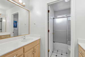Bathroom featuring vanity and shower / bath combination with glass door