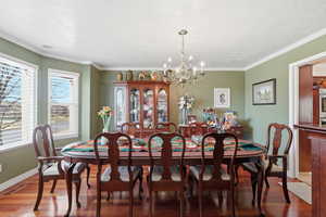 Dining space featuring wood finished floors, suspended lighting, and ornamental molding