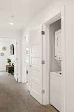 Laundry area featuring stacked washer / dryer, light carpet, and recessed lighting