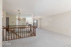 Empty room with a wainscoted wall, light carpet, a chandelier, and a textured ceiling