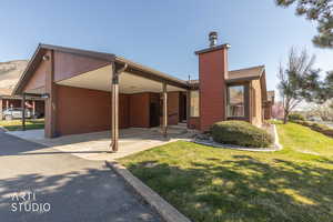 View of front of home featuring a front yard, a chimney, and a carport