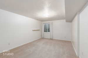 Empty room with a textured ceiling and light carpet