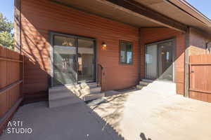 View of exterior entry featuring brick siding, a gate, and a patio