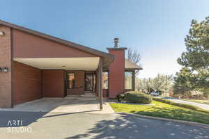 View of front of property featuring a front yard, an attached carport, and driveway