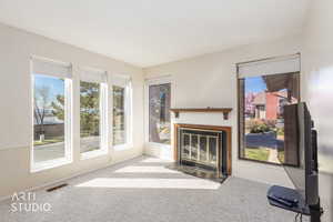 Unfurnished living room featuring a fireplace with flush hearth and carpet floors