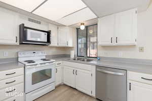 Kitchen featuring white appliances, white cabinetry, and light countertops