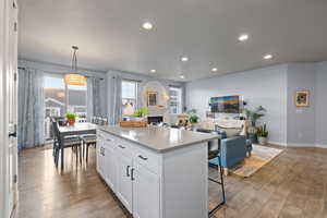 Kitchen with open floor plan, a center island, white cabinetry, light wood-style floors, and a kitchen bar