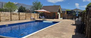Rectangular inground swimming pool with integrated spa, surrounded by stamped concrete patio