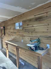 Dining space with wooden walls, concrete flooring, and a workshop area