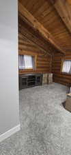 Bonus room with log walls, carpet, lofted ceiling with beams, and wooden ceiling