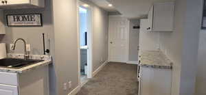 Kitchen with white cabinets, dark colored carpet, light stone counters, and recessed lighting