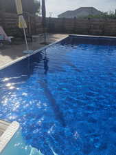 View of swimming pool with a fenced backyard and patio surround