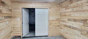Hallway featuring wood walls and unfinished concrete floors
