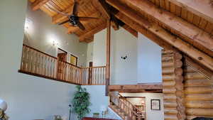 Stairway featuring a high wooden beamed ceiling, a ceiling fan, and rustic walls