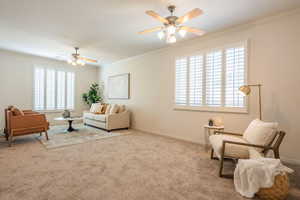 Living area with a ceiling fan, crown molding, and carpet flooring