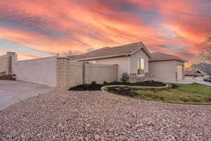 Property exterior at dusk featuring stucco siding, stone siding, a gate, a tile roof, and a garage