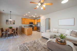 Kitchen featuring open floor plan, a peninsula, stainless steel appliances, arched walkways, and a ceiling fan